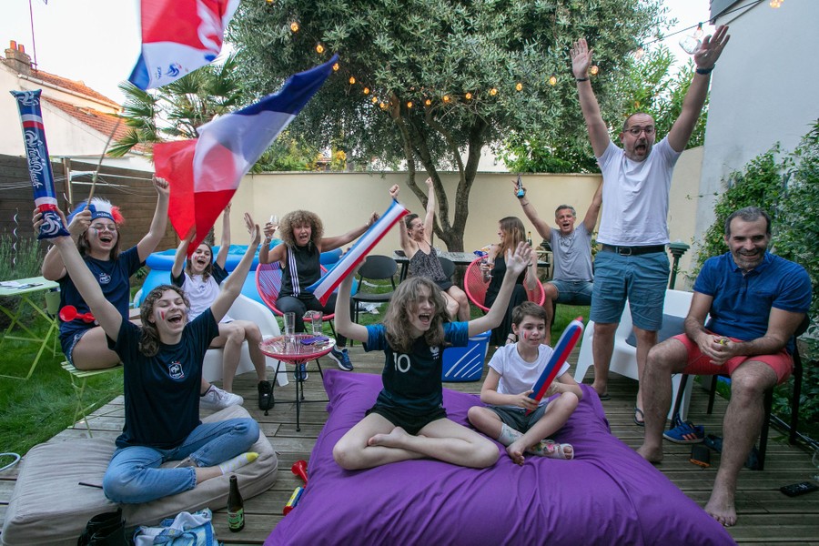A small group of football fans watch a match together in a garden.