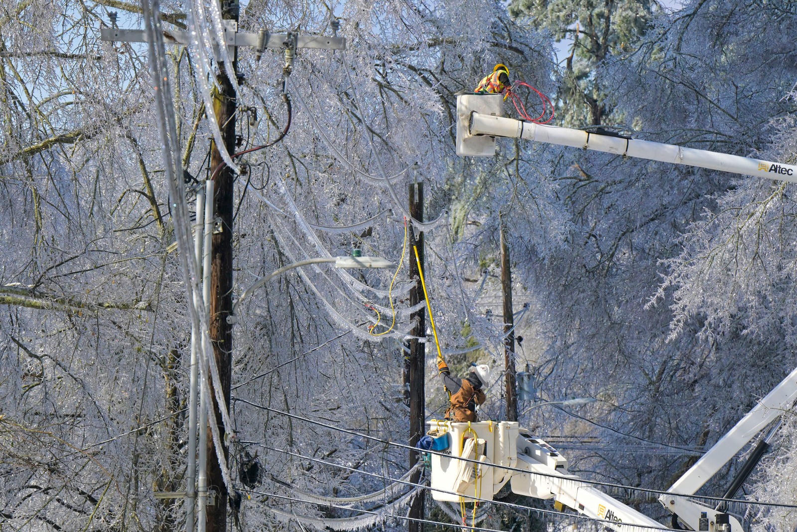 Utility crew members work on ice-encrusted power lines.