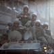 Heavily armed Russian soldiers ride atop an armored tank in Aleppo.