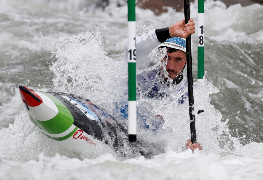 A kayaker passes through gates in white water during a competition.