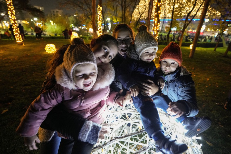 Children pose on top of a light installation at a Christmas fair.