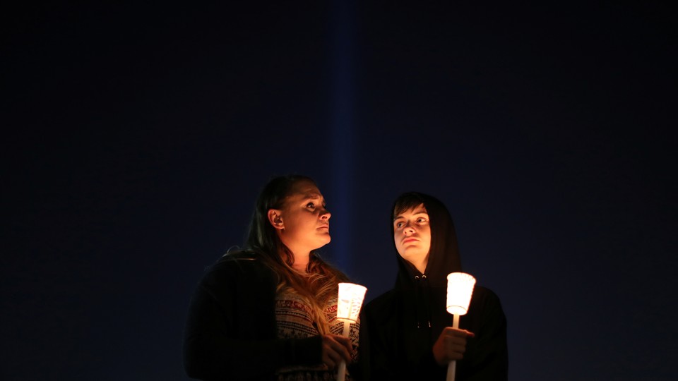 People hold candles at a vigil.