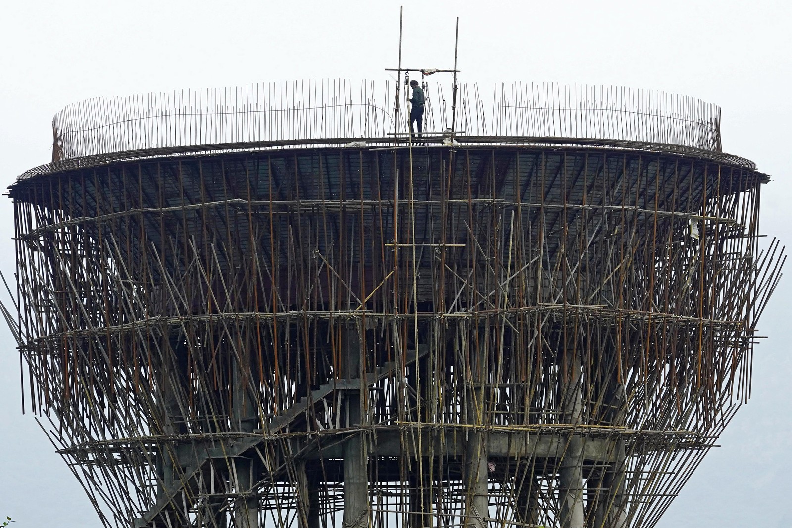 A person walks atop an under-construction water tower.