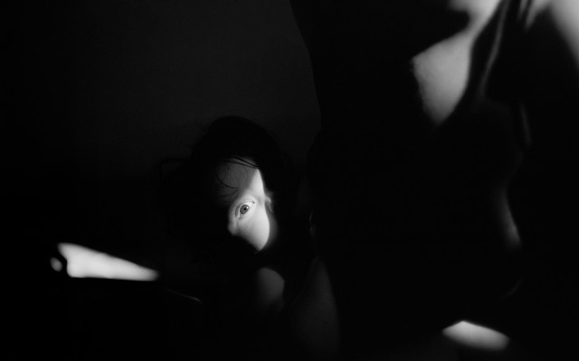 A baby's eye caught in the sunlight in mothers arms