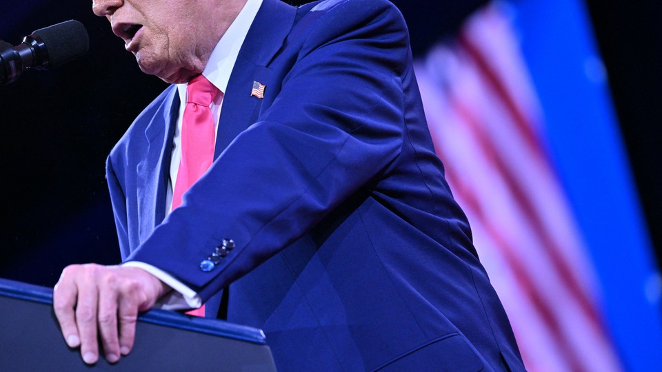 Donald Trump grips the podium and speaks into a microphone at a CPAC event