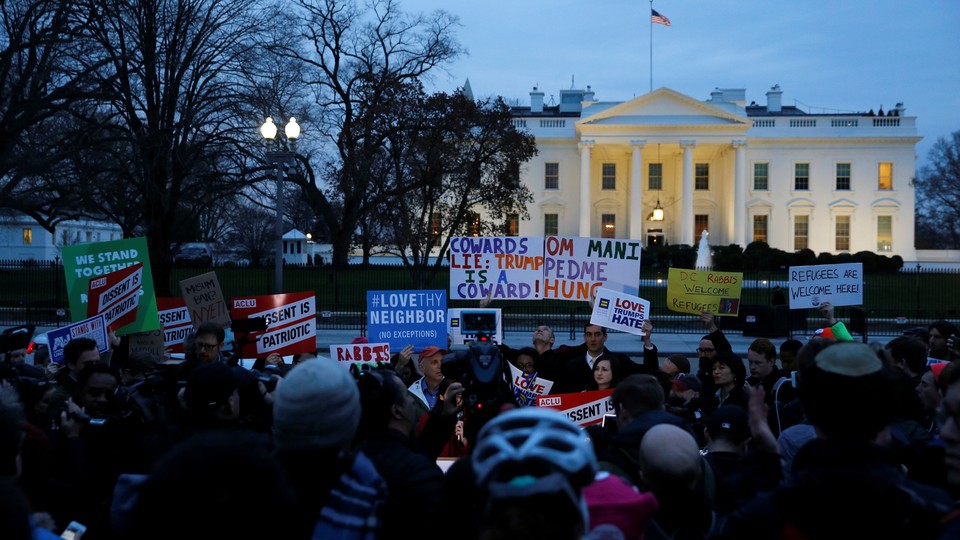 Demonstrators rally against the Trump administration's new travel ban outside of the White House.