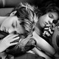 a black and white photo of two girls asleep while sitting, one leaning on the other