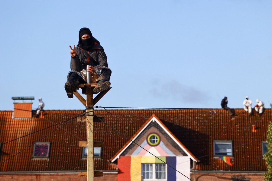 Several protesters sit on top of a pole or on top of a roof.