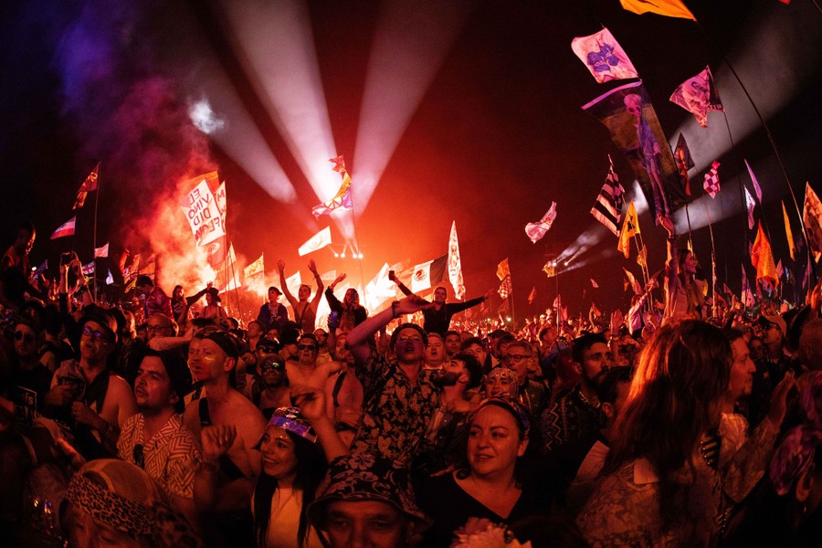 A crowd of people watch a concert, seen from the front of the stage.