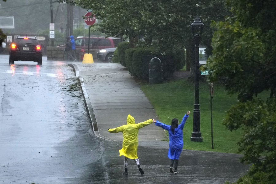 Two people dance in the rain alongside a road.
