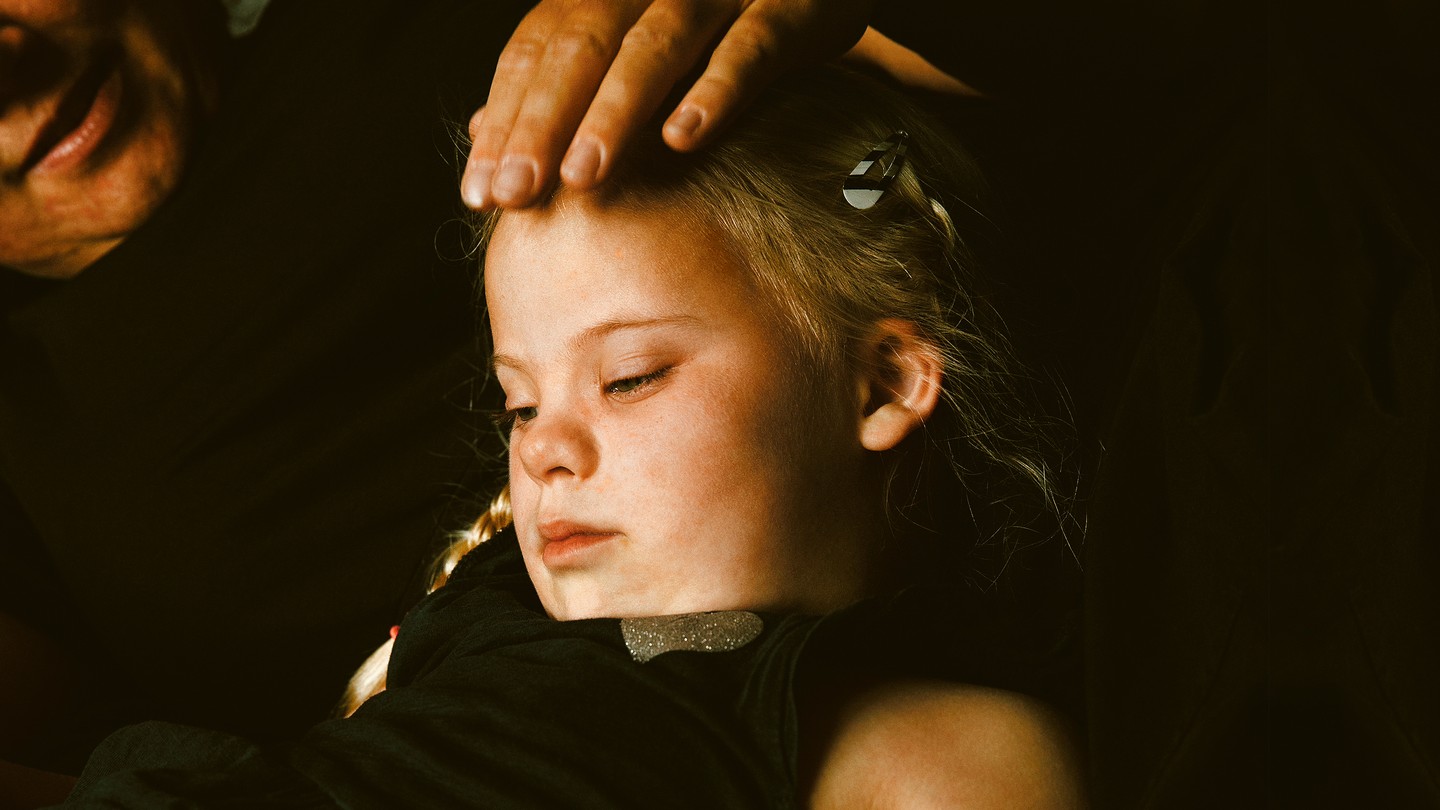 parent with hand on head of young girl