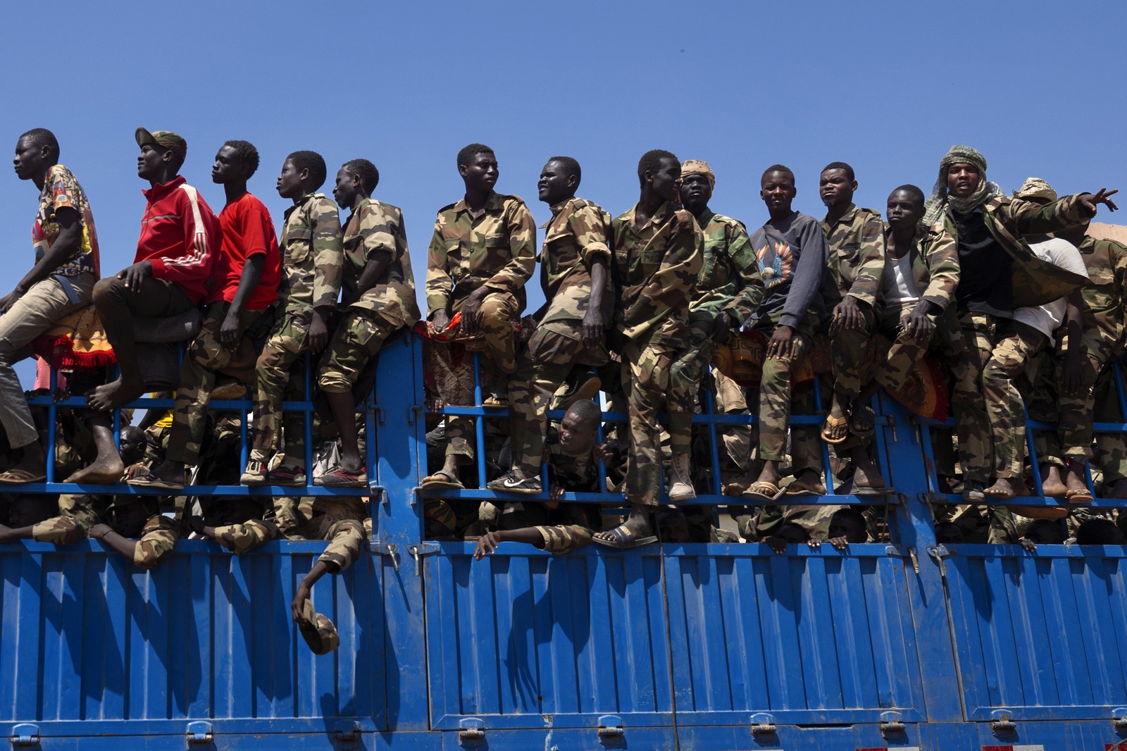 A group of men riding on a truck drive through
