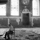 A man sits alone in a ruined synagogue in Russia.
