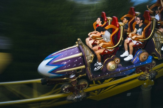 People on Stardust Racers, a purple and blue roller coaster with red chairs at Universal Epic Universe