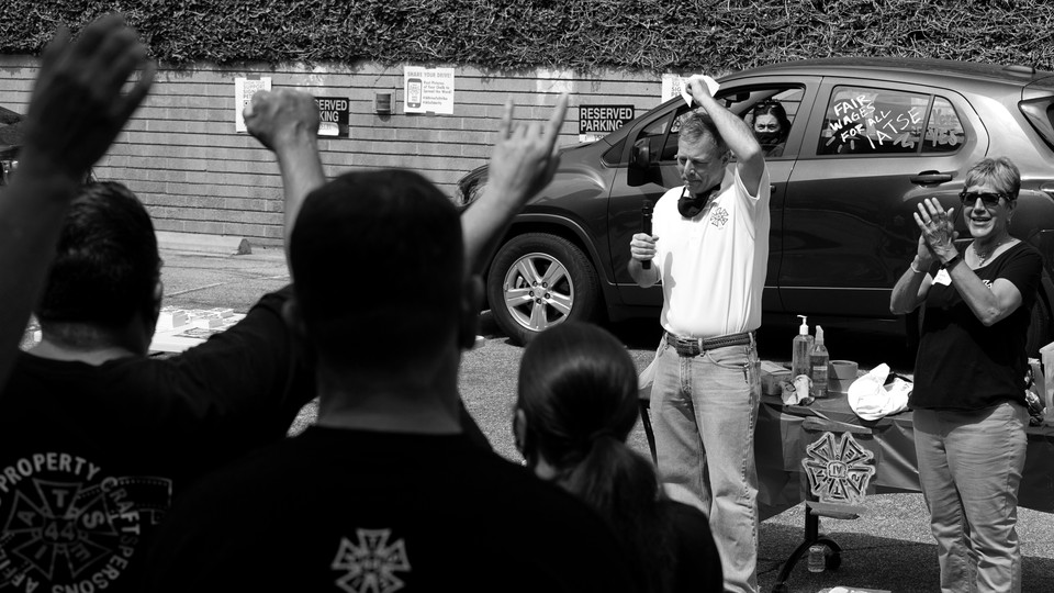 Black and white photo of Mike Miller, vice president of the International Alliance of Theatrical Stage Employees, speaking to members at a rally