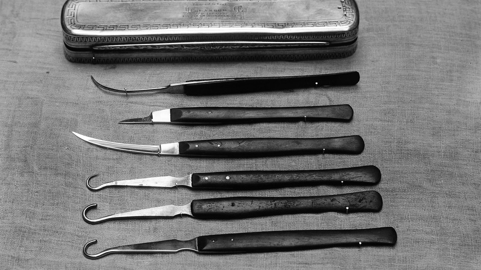 A set of silver and black surgical instruments and a silver case