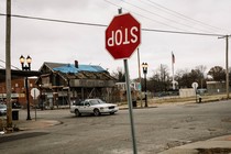 a street in a state of abandonment and disrepair with an upside down Stop sign