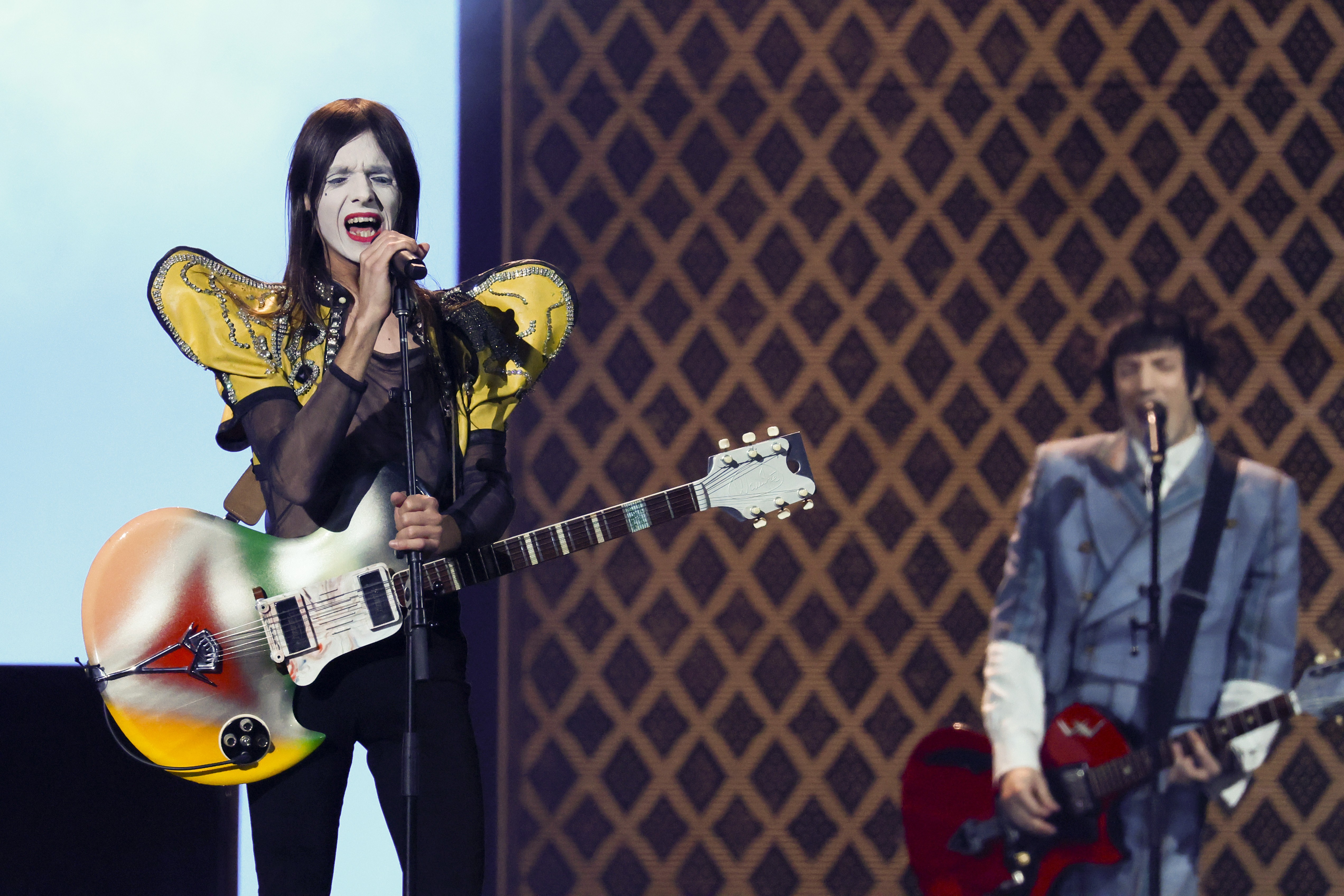Two performers sing while playing guitar.