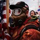 An insurrectionist wearing a gas mask and holding an American flag on January 6 