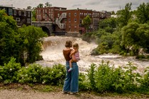 Photograph of a mother holding her daughter in front of an overflowing river in Vermont