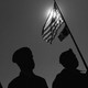 Veterans standing beneath a raised American flag