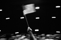 Black-and-white image of a person waving an American flag