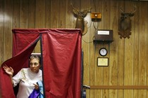 A woman leaves a voting booth with a blue curtain, set in front of hunting trophies, in Danielsville, Pennsylvania