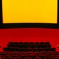 View of movie theater seats and screen, in black, red, and yellow