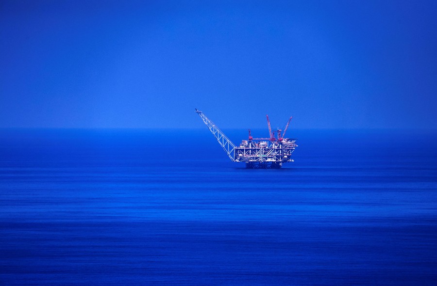 A natural-gas rig stands alone in an ocean.