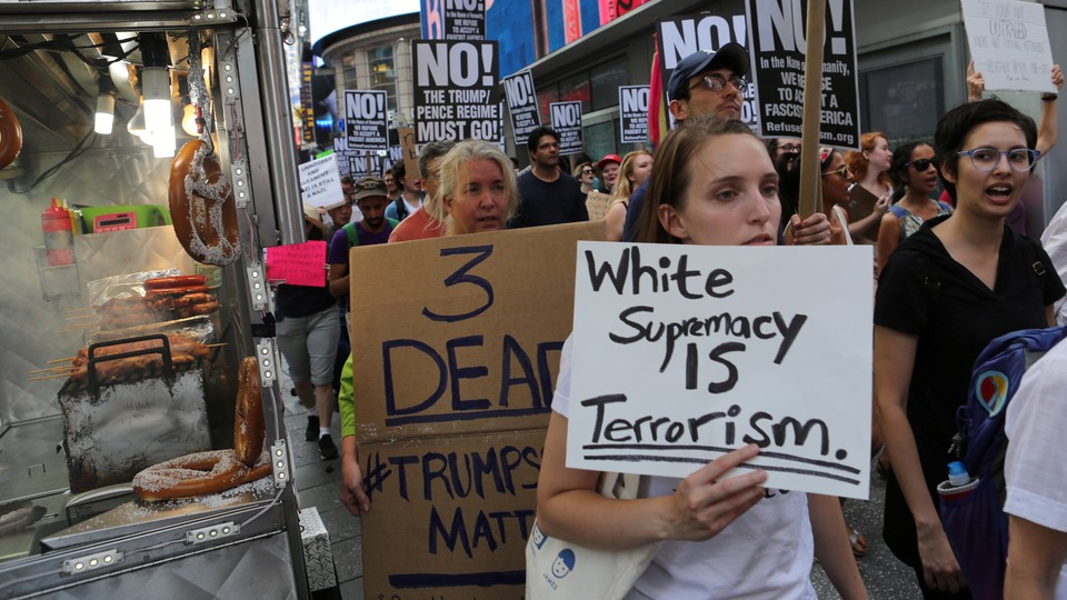 A protester in a march holds a sign reading "White supremacy is terrorism."