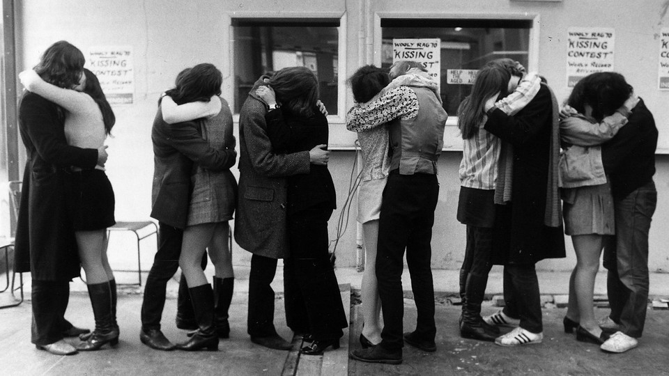 A black-and-white photo of multiple couples kissing