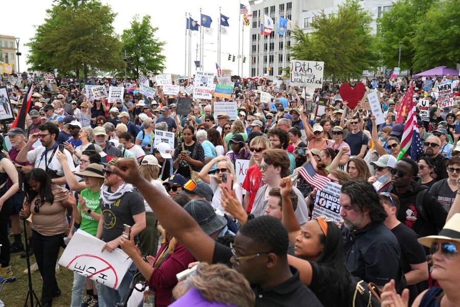 Many protesters hold up signs.
