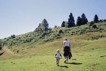 A photo of a parent and a child walking across a grassy expanse