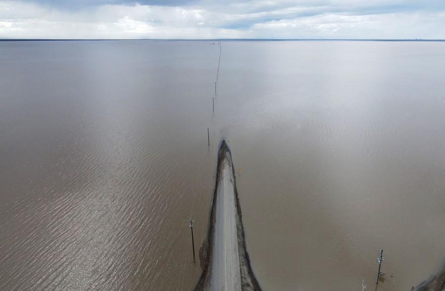 An aerial view of a road disappearing into a flooded plain