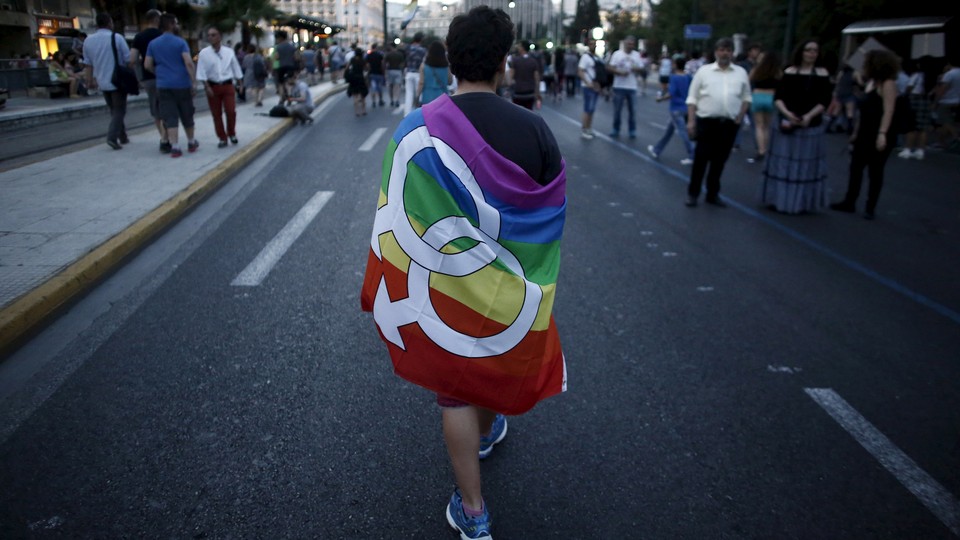 A gay-rights activist wearing a rainbow flag walks through the city center during a Gay Pride parade.