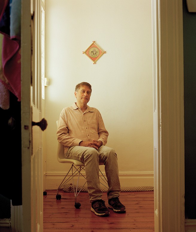 photo of man sitting in rolling office chair viewed through doorway