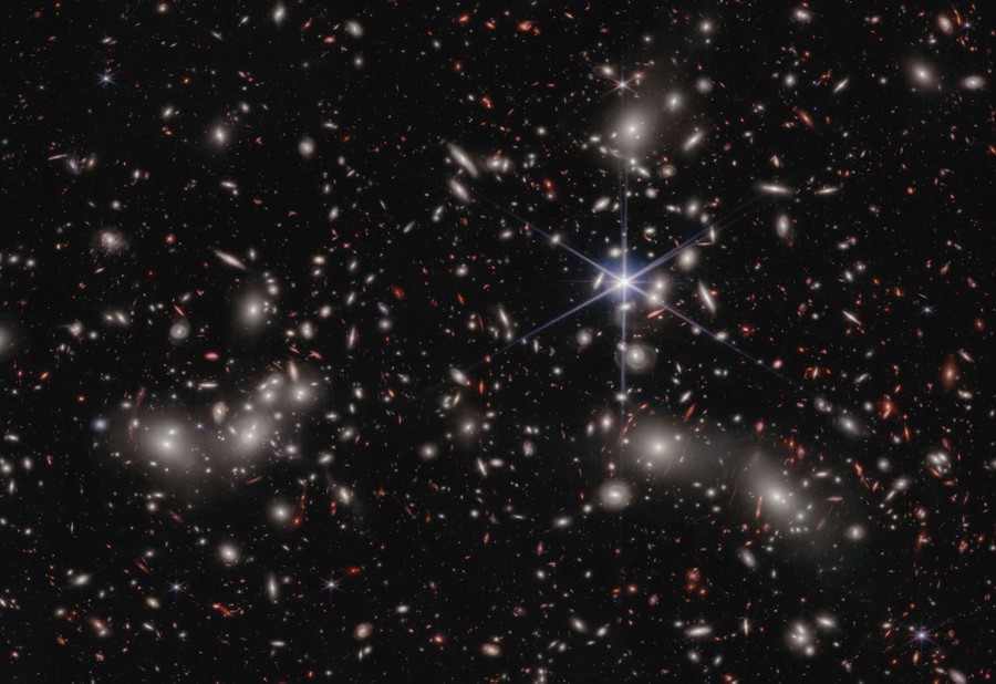A jumble of galaxies and galaxy clusters fills an image of deep space.