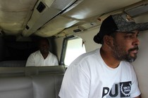 Two men sitting inside an airplane. One is looking out a window.