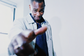 photo of Dave Chappelle next to window pointing at viewer with hand in foreground