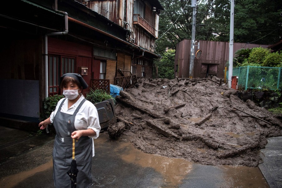 A person stands near mud and debris in a street.