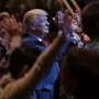 Donald Trump, standing among a group of churchgoers, claps during a worship service in Las Vegas.
