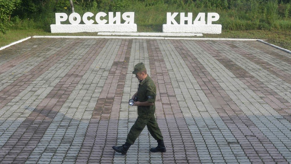 A guard walks along a platform past signs, which read "Russia" and "DPRK."