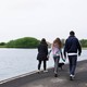 A teenager and her parents walk their dog along a river.