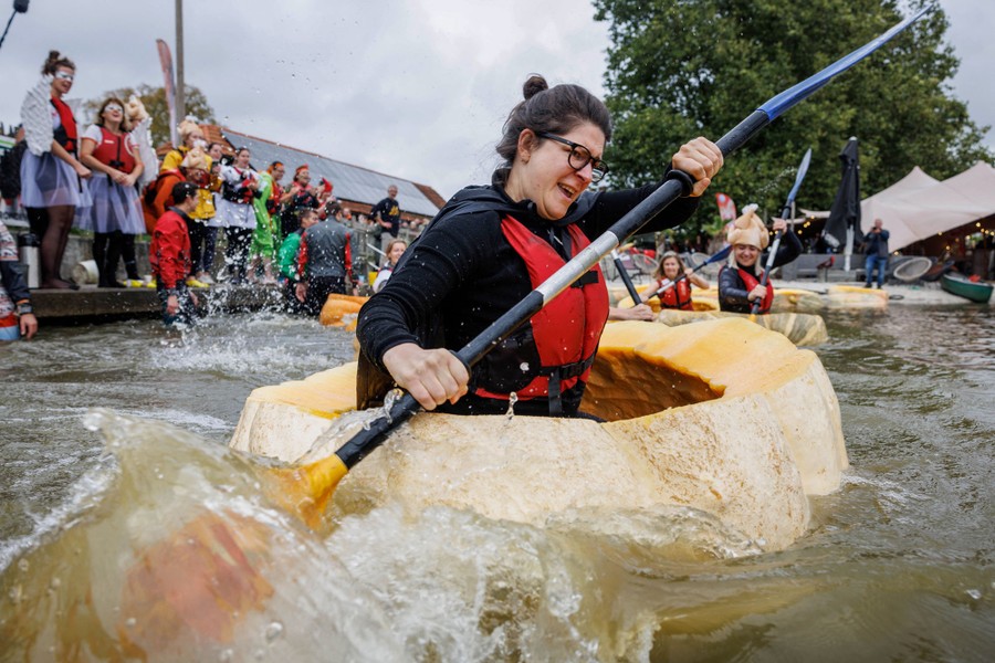 A participant paddles in a hollowed-out giant pumpkin.