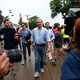 The Democratic presidential candidate Tom Steyer walks through the Iowa State Fair in Des Moines. People are surrounding him. One person, in the foreground, is pointing a camera at him.