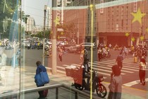 Chinese flags and pedestrians reflected in a window in Shanghai, China