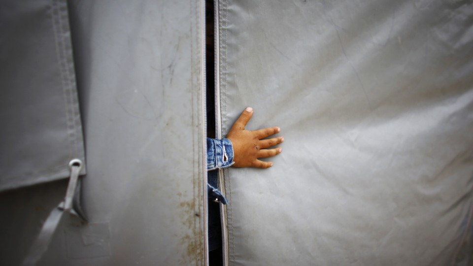 A refugee boy from the Syrian town of Kobani sticks his hand out of a tent in a refugee camp.