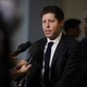Sam Altman in a suit in front of microphones