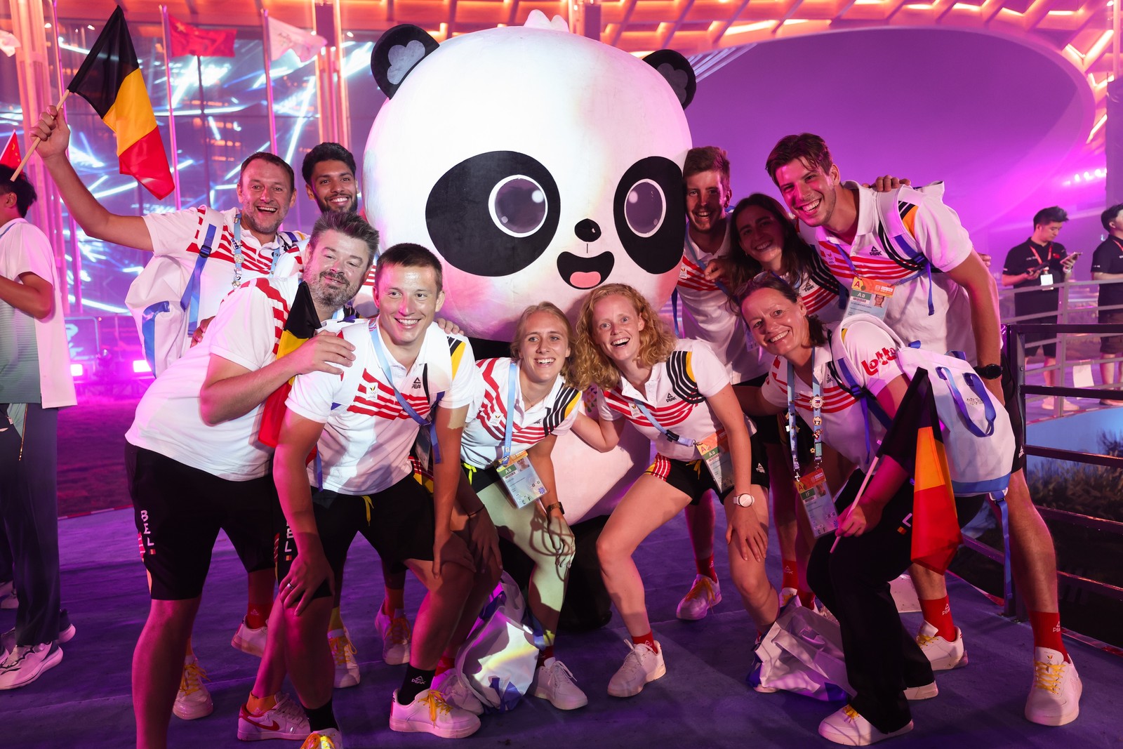 A group of Belgian athletes pose for fun with a large panda mascot.