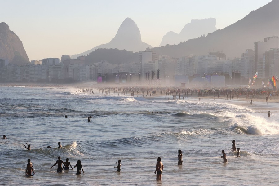 People swim and play in the surf along a long beach in Rio de Janeiro.